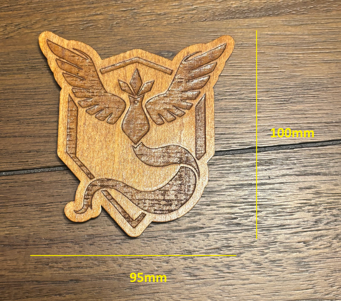 Stained basswood fridge magnet of a the Team Mystic logo from the Pokemon video games