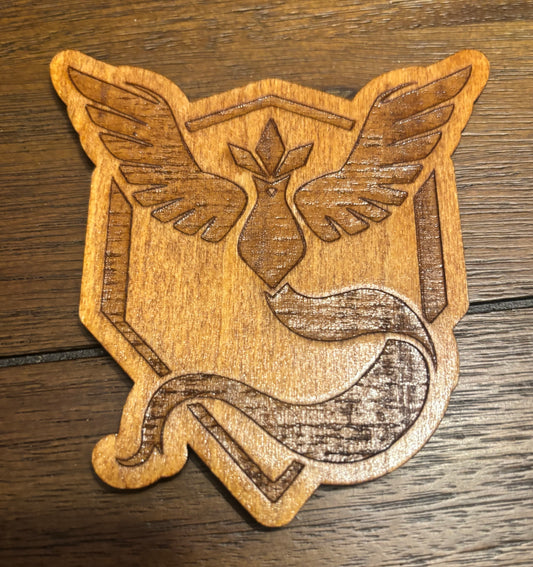 Stained basswood fridge magnet of a the Team Mystic logo from the Pokemon video games
