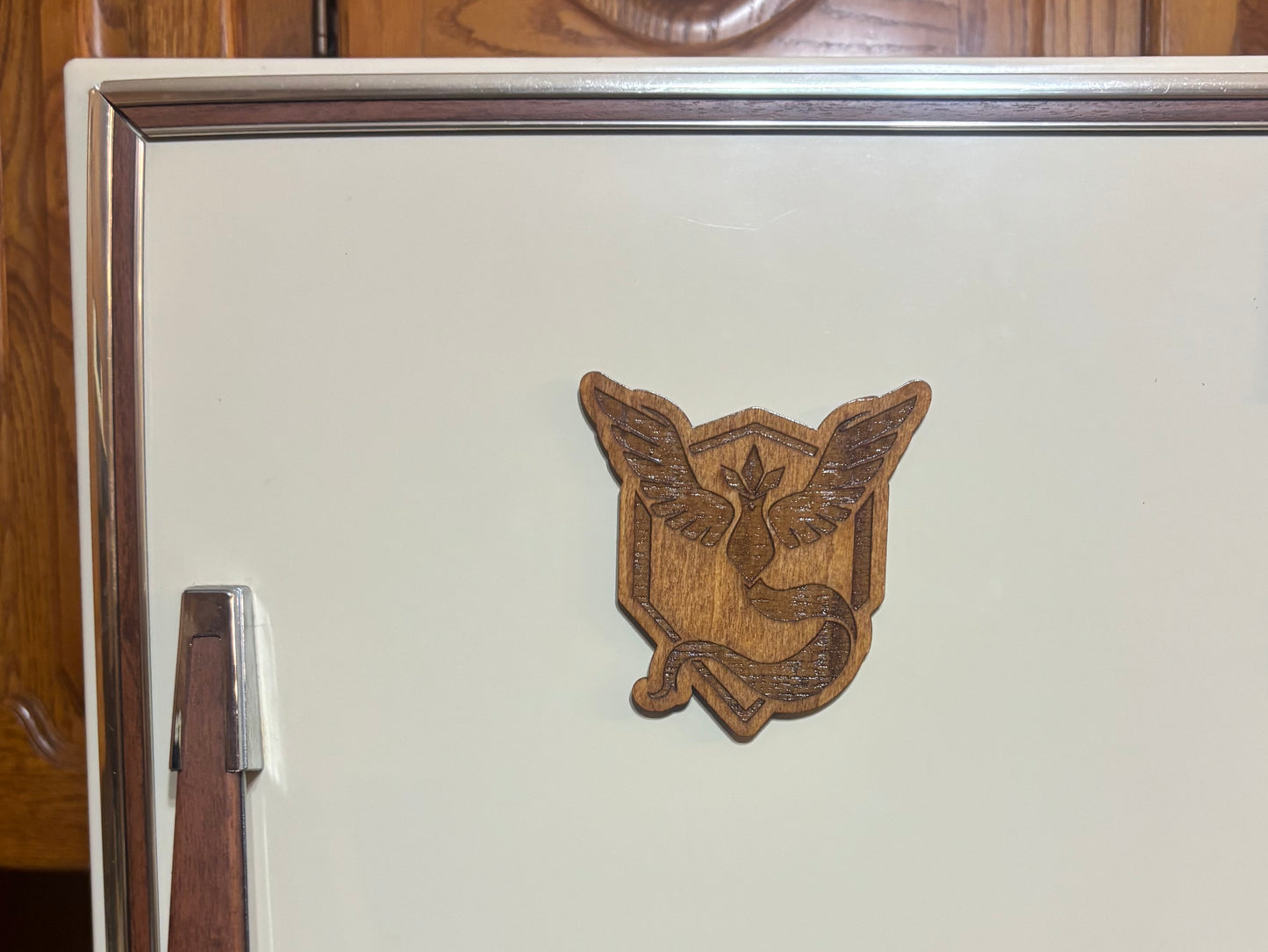 Stained basswood fridge magnet of a the Team Mystic logo from the Pokemon video games