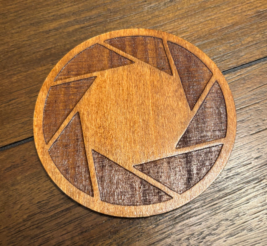 Stained basswood fridge magnet of the Aperture logo from the Portal video game