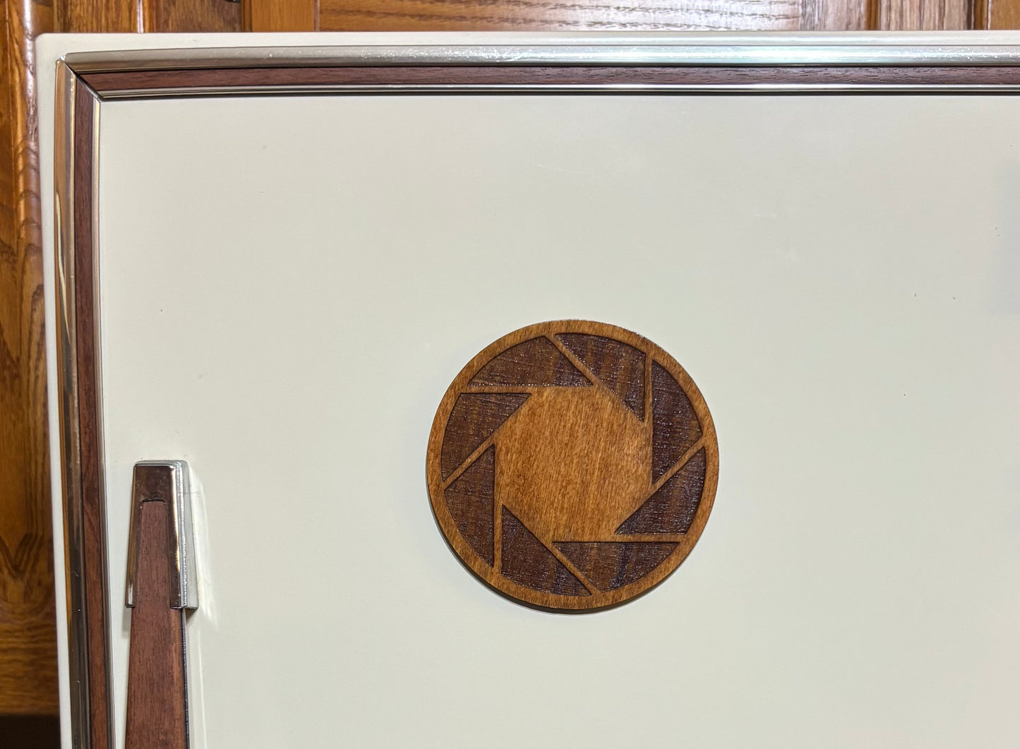 Stained basswood fridge magnet of the Aperture logo from the Portal video game